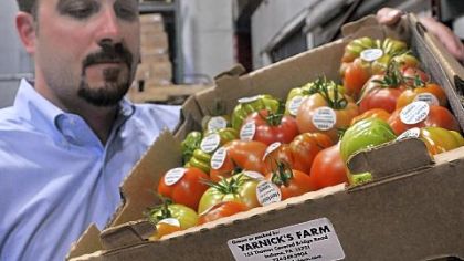 John McClelland, vice president of procurement and strategic development at Paragon Foods, checks a carton of heirloom tomatoes that carries stickers indicating they were grown or packed by a local firm.