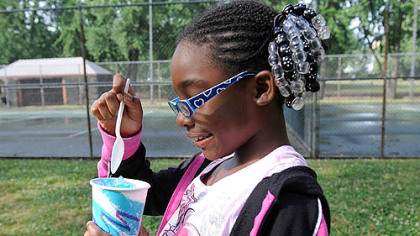 Lovie Blackman, 8, of Sheridan, starts her summer cooldown early as she digs into a blueberry ice ball on Monday in West Park on the North Side.