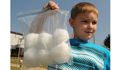 Cory Thurston, 8, carries the six snowballs he saved in the freezer from last winter.