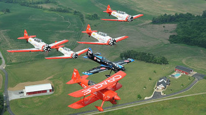 Pilots Sean D. Tucker in the Oracle Challenger 3 (red) and Rob Holland in a MXS fly in formation with members of the Aeroshell Aerobatic Team during a Thursday practice flight in preparation for this weekend's air show at the Westmoreland County Airport.