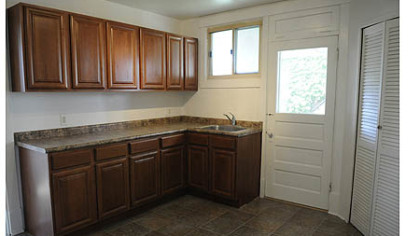 The second floor kitchen has a built-in pantry and offers hardwood cabinetry and laminate countertops with vinyl tile flooring.