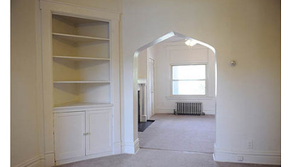 The living room has a decorative mantel with built-in cabinets on either side as well as a distinctive Tudor arch.