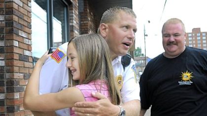 Allysa Parham, 13, gets a hug from Clairton police Chief Rob Hoffman on Friday outside M&M Uniforms in Bridgeville.