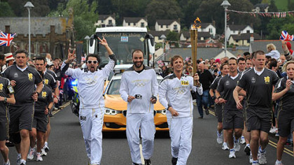 Torchbearers Matt Bellamy, Dominic Howard and Christopher Wolstenholme, from the band Muse, carry the Olympic Flame on the leg between Torquay and Teignmouth.