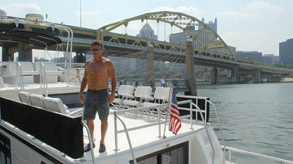 Dave Wingrove, of Belle Vernon, stands on his boat "Still Cruising" on Friday morning outside of Heinz Field. Wingrove and many others have docked their boats on the North Shore in preparation for the Kenny Chesney concert weekend.