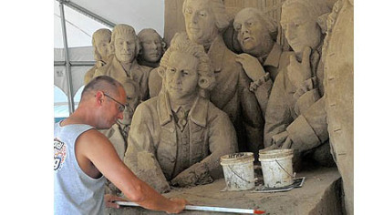 Thomas Koet, working on Thursday with Sandsational of Melbourne, Fla., works on a sand sculpture based on the signing of the Declaration of Independence. It is being readied for the Three Rivers Regatta.