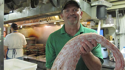 Ron McFarlain, owner of Cajun Connection in Utica, Ill., holds a piece of alligator he gets from his native Louisiana.