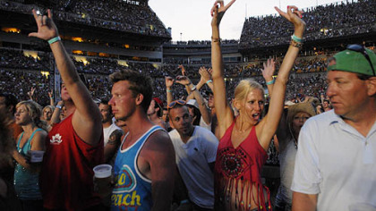The crowd cheers, dances and sings as Kenny Chesney performs.