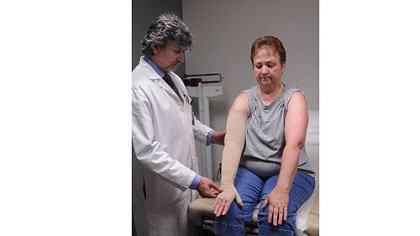 Dr. Atila Soran, director of UPMC's Lymphedema Education, Screening, Early Detection and Prevention Program, examines the compression bandage on Josie Grimm.