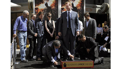 Christopher Nolan, center, director of the  film "The Dark Knight Rises," is surrounded by cast members from the film as he takes part in his hand and footprint ceremony at Grauman's Chinese Theatre on Saturday.