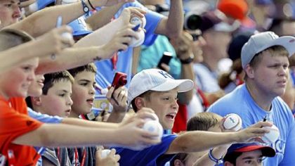 Fans, with balls and pens in hand, seek autographs during All-Star Game batting practice.
