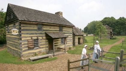 Tour guides Zoe Johnson, left, and Kaitlin Davis walk from the cabin that re-creates a tavern and courtroom from the era of  the American Revolutionary War in Historic Hanna's Town.