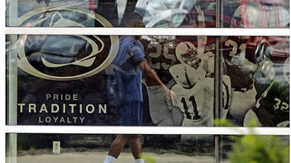 A student is reflected in the window of the Mildred and Louis Lasch Football Building on Penn State's main campus in State College.