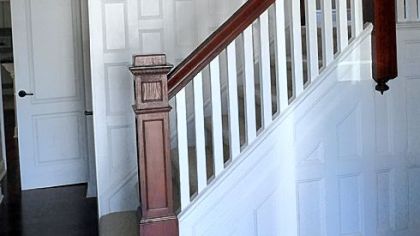 In the large entryway, the wood was was stripped, the paneling was painted white, and the rails and banisters were restored to a deep cherry.