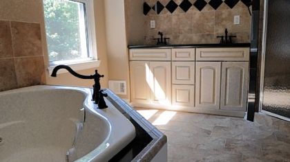 The master bathroom features a corner whirlpool tub, double-vanity sinks, ceramic tile and a separate shower that has a built-in seat.