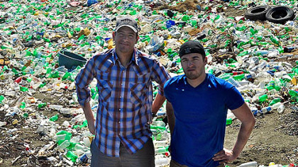 Ian Rosenberger, founder and CEO of Thread LLC, and Frank Macinsky, marketing director, stand in front of plastic waste in Haiti. Thread LLC is transporting 50,000 pounds of plastic flakes from Port au Prince's streets to the United States, where it eventually will be extruded into fiber.