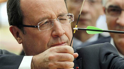French President Francois Hollande aims as he prepares to shoot an arrow during a visit with members of the French Archery team for the London Olympics 2012, at their training headquarters in Paris, Monday, July 16, 2012.