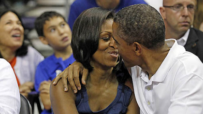 President Barack Obama leans in to kiss first lady Michelle Obama for 'Kiss Cam' while attending an Olympic exhibition basketball game, Team USA and Brazil, Monday, July 16, 2012, in Washington.