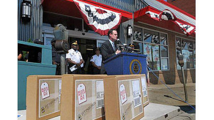 Mayor Luke Ravenstahl speaks in front of the IGA in Beechview, with "Block Watch in a Box" boxes in the foreground.