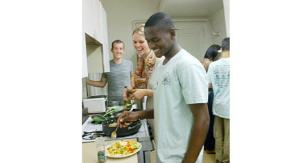 Instructors Will Grove and Kelsey Weisgerber look on as Allderdice High School intern Mberwa Mada builds a super taco.