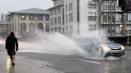 A vehicle creates a splash on Forbes Avenue near Carnigie Mellon University during an afternoon thunderstorm on Wednesday.