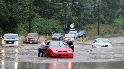 Jason Donahue, left, of Clairton and Dustin Tichenor of Bethel Park push their vehicle to safety after it was stranded in rising water on Route 51 near Bausman Street.