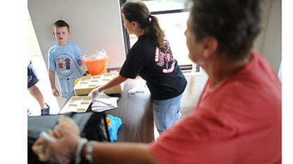 Cafeteria cooks Mary Bish, center, and Barb Rush, right, prepare to serve Robin Tracy, 9, as he walks up to the counter as the Central Greene School District's Summer Food Service Program makes its daily stop at the Valley Farm Drive apartments in Waynesburg.