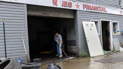 Rick Ibrahim sweeps out water Saturday from Best Auto Mart in the South Hills. There were several feet of water inside his store Friday after strong storms caused a flash flood.