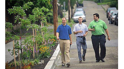 From left, The Penn State Center interns Derek Thomas, Preston Linck and Justin Polosky walk past the newly created Four Mile Run bioswale, a stormwater mitigation project that they helped create, before a ribbon cutting Friday on Saline Street in Greenfield.