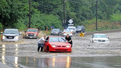 Jason Donahue, left, of Clairton and Dustin Tichenor of Bethel Park push their vehicle out of rising floodwaters on Route 51 near Bausman Street on Friday.