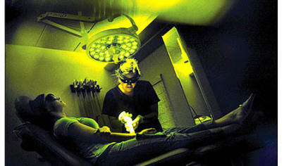 Kat Mahoney, photographed at the Aesthetic Laser Center through protective glasses, removes a tattoo Friday.