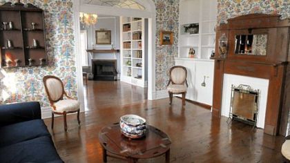 A parlor has a view into the living room, which has picture-frame molding and Wedgwood blue walls.