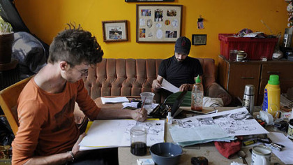 Daniel McCloskey illustrates his comic, "Top of the Line," while visiting writer Matt Whispers of Chicago works on his poems at the artist collective Cyberpunk Apocalypse.
