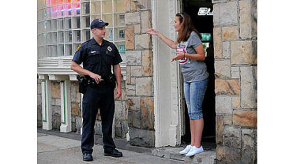 Pittsburgh police Officer Brett Butkewich of the Zone 3 station listens to comments from a concerned woman in the doorway of Mooney's Place on Brownsville Road in Carrick.