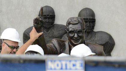 Workers handle the statue of former Penn State football coach Joe Paterno before removing it.