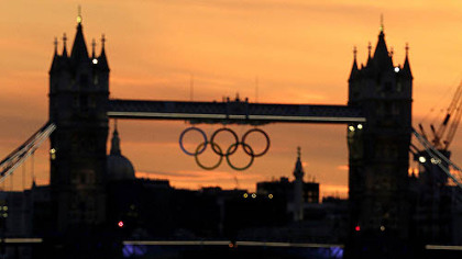 The sun sets behind London's landmark Tower Bridge with a display of Olympic rings in the distance on Saturday, July 21, 2012, in London. The 2012 London Olympics open this Friday.