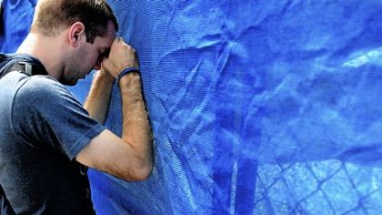 Recent Penn State graduate Patrick Thorp has a moment of silence Sunday at the fence that blocks the site of the Joe Paterno statue after its removal.