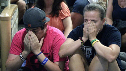Andrew Hanselman, left, of Bucks County, and Maddy Pryor, from Neptune, N.J., react as they listen to a the NCAA announcement in the HUB on the Penn State University main campus in State College today.