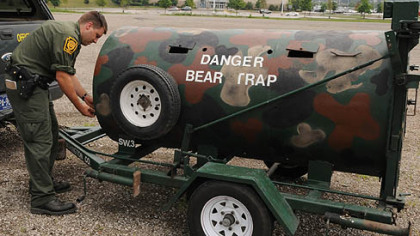 Officer Matt Kramer, with the Pa. State Game Commission, closes the door used for feeding  in the front of   the "Bear Trap" , near the Pittsburgh Mills Mall in Frazer Township.