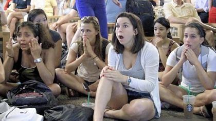 Laura Lovins, a Penn State sophomore from State College, center, is among a group listening to the television in the school's HUB in University Park as the NCAA sanctions against the football program are announced on Monday.
