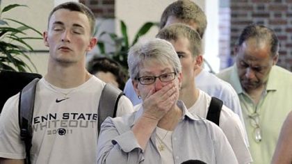 Susan DelPonte, center, of State College, a Penn State employee and student advocacy specialist, reacts Monday in the Hetzel Union Building on the Penn State campus as the NCAA sanctions against the Nittany Lions are televised.