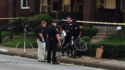 Pittsburgh police officers examine the bicycle that was struck by a white car early Wednesday morning.