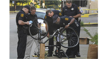 Police officers examine the bike belonging to James Price of Homewood, who was struck and killed by a hit-and-run driver on Penn Avenue early Wednesday.