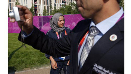 A man takes a photo near Tahmina Kohistani, Afghanistan's only female athlete, after attending the Olympic Team Welcome Ceremony at the Athletes' Village.