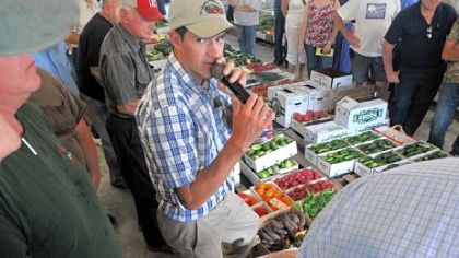 Auctioneer Andrew Yoder watches for a higher bid on a box of beets as he deals with the merchandise at the Tri County Produce Auction.