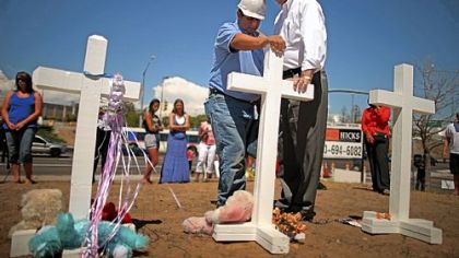 Greg Zanis, left, a carpenter from Aurora, Ill., prays with Aurora, Colo., Mayor Steve Hogan at the 12 crosses Mr. Zanis made for a makeshift memorial to the victims of the weekend's mass shooting in suburban Denver.