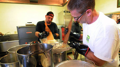 Parish members Tim Polas, left, and John Kirish, right, scrape halushky batter into boiling water to make the church's signature dish -- potato dumpling halushky at St. John the Baptist Orthodox Church in Ambridge.
