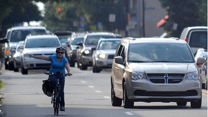 A woman bicycles through Wednesday evening's rush-hour traffic on Penn Avenue near Braddock Avenue.