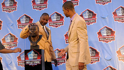 Chris Doleman pats his bust as his son Evan Doleman stands by after the former Pitt standout was welcomed into the Pro Football Hall of Fame Saturday night in Canton, Ohio.