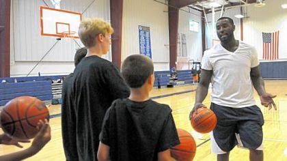 DeJuan Blair of the NBA San Antonino Spurs explains a drill for campers at his basketball day camp at Aquinas Academy in Hampton.